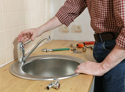Close-up of plumber using a pipe wrench beneath a bathroom vanity