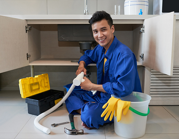 Plumber feeding a motorized drain snake into a floor drain indoors